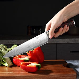 Main tenant couteau chef Paudin lame Damascus – découpe poivron rouge sur planche bois cuisine moderne