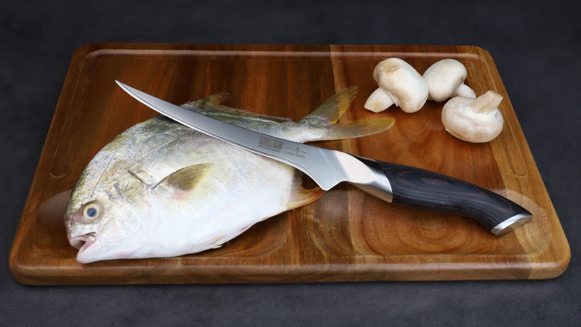 Couteau à filet Hoshanho Loong Series lame flexible manche noir avec poisson et champignons sur planche acacia