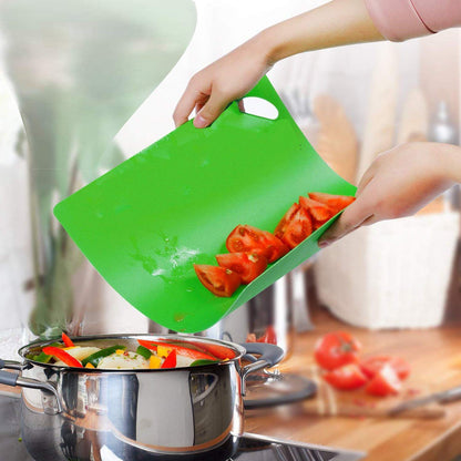 Planche à découper plastique verte flexible – versement tomates coupées dans casserole inox en cuisine