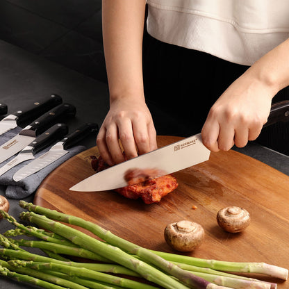 Couteau Keemake santoku découpant de la viande sur planche en bois avec asperges et champignons